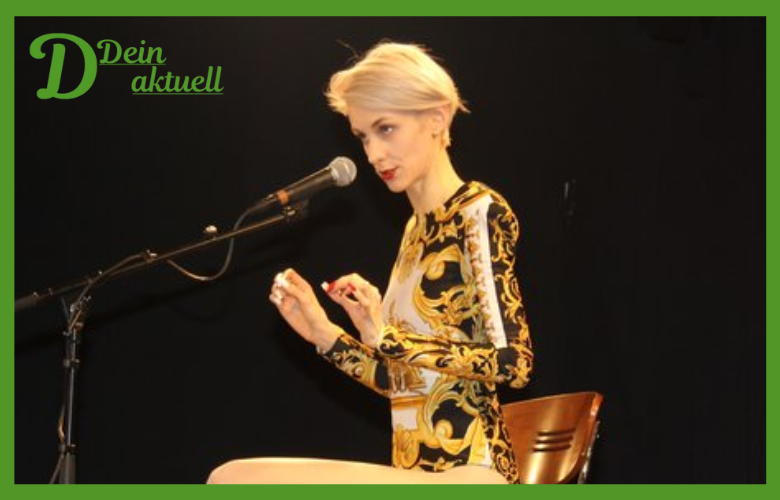 Lisa Eckhart auf der Bühne in elegantem schwarzen Kleid, schlanke Figur betont ihr Bühnenimage